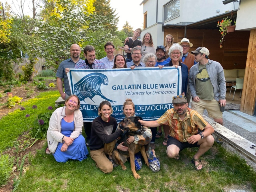 A group of people (and a dog) with a sign that reads "Gallatin Blue Wave."