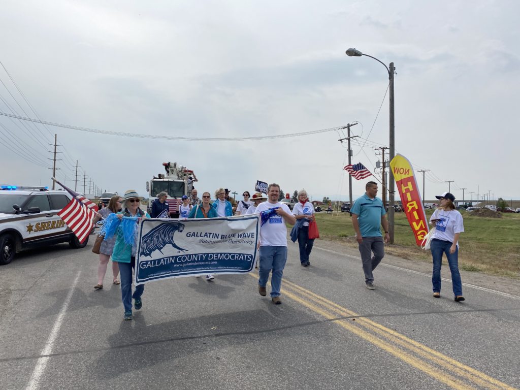 People marching down the road in Manhattan, MT with a Gallatin Democrats banner.